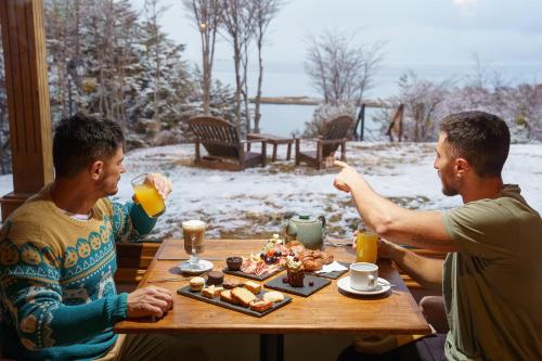 two men sitting at a table with food and drinks at Los Ñires Ushuaia in Ushuaia