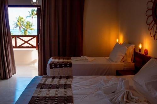 a hotel room with two beds and a window at POUSADA E RESTAURANTE GAROUPA in São Miguel dos Milagres