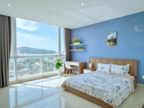 ブンタウにあるCăn Hộ OASKY,3 Phòng View Đẹp Nhìn Ra Biển,Núi Và Hồ Bàu Senの青い壁のベッドルーム1室、ベッド1台、デスクが備わります。