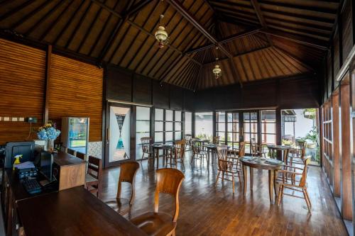 ein Esszimmer mit Tischen, Stühlen und Fenstern in der Unterkunft Shankara Munduk Bali in Munduk
