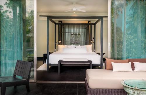 a bedroom with a bed and a couch at Twinpalms Phuket in Surin Beach