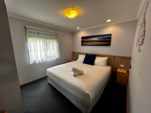 1 dormitorio con 1 cama grande con colcha blanca en Big4 Ulladulla Beachside Holiday Park, en Ulladulla