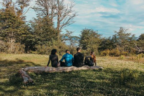 a group of four people sitting on a tree log at Los Ñires Ushuaia in Ushuaia