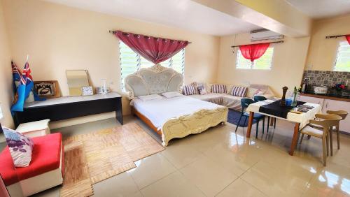 a bedroom with a bed and a couch and a table at Pacific Paradise Villa in Sigatoka