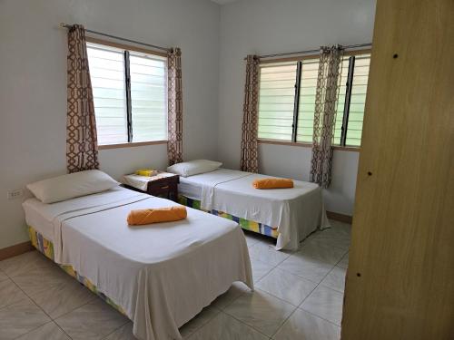 two beds in a room with two windows at Jackys homestay in Bug-ong