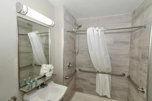 a bathroom with a sink and a shower with a mirror at Rock Island Inn & Suites Marshalltown in Marshalltown