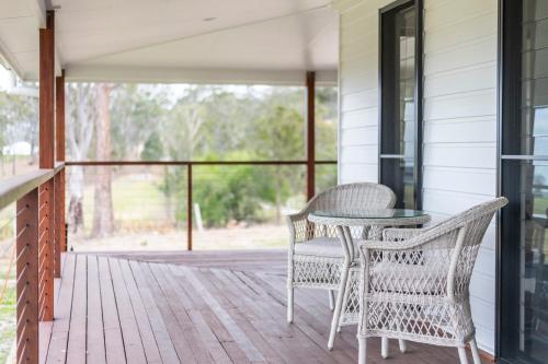 a porch with two chairs and a table on it at Farmstay - LJHooker Yamba in Maclean