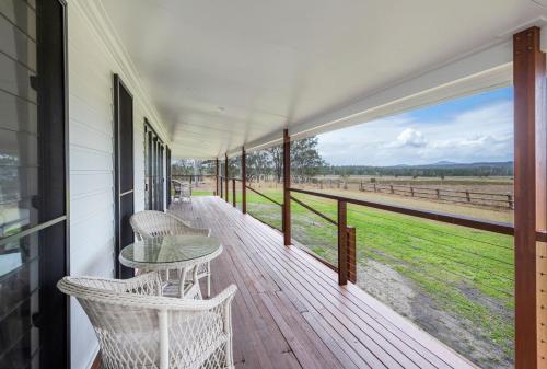 a porch with a table and chairs and a view of a field at Farmstay - LJHooker Yamba in Maclean