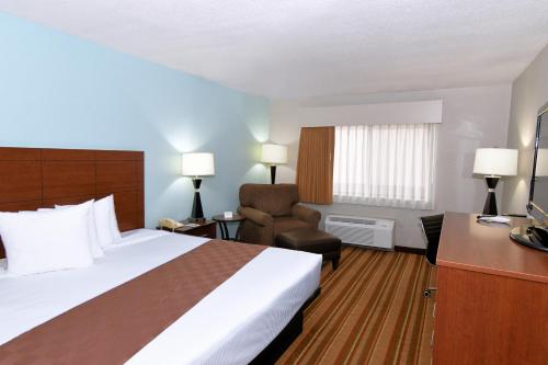 a hotel room with a bed and a chair at Rock Island Inn & Suites Marshalltown in Marshalltown