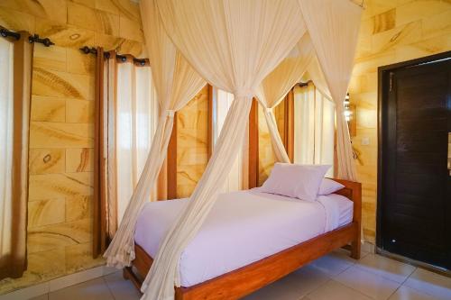 a bedroom with a bed with a canopy at Mejan Home Stay in Balian