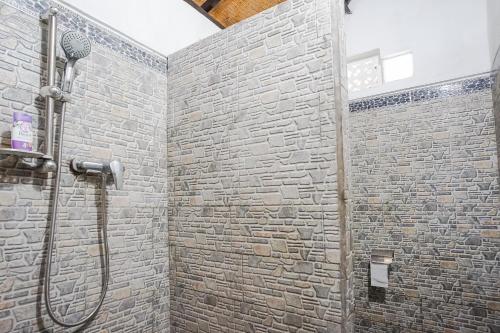 a bathroom with a shower with a stone wall at Mejan Home Stay in Balian