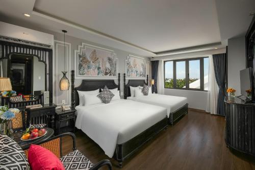 a bedroom with two beds and a living room at Serene Nature Hotel & Spa in Hoi An