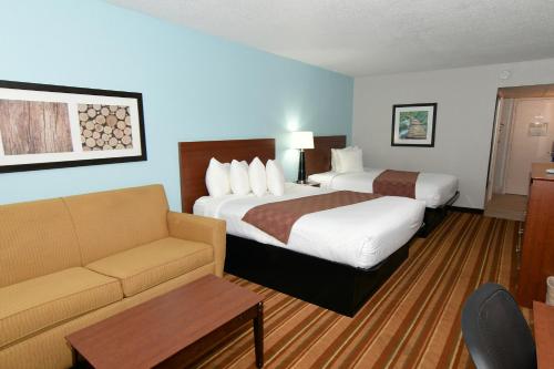 a hotel room with two beds and a couch at Rock Island Inn & Suites Marshalltown in Marshalltown
