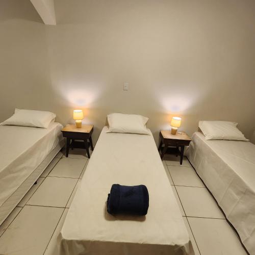 two beds in a room with two lamps and a bag at CASA IMPERIAL HOTEL POUSADA in São Luís