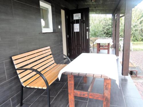 a wooden bench and a table on a porch at Holiday House near Lake D bie in Lubczyna