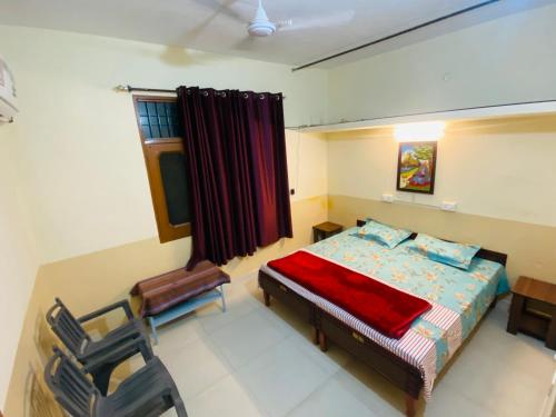 a bedroom with a bed and a chair and a window at Negi Lodge Chandigarh in Chandīgarh