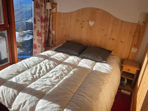 un grand lit dans une chambre avec une fenêtre dans l'établissement Appartement duplex 4 pers à Arc 1800, balcon, Wi-Fi, accès pistes et commerces à proximité - FR-1-411-912, à Bourg-Saint-Maurice
