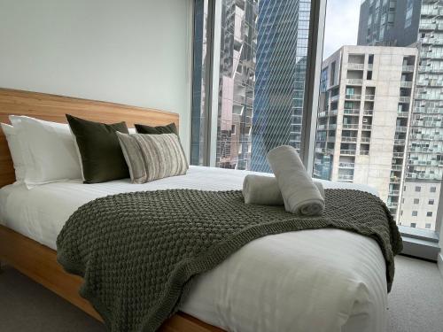 a bedroom with a large bed and a large window at Serenity Stayz - 3 Bedroom Apartment in Melbourne CBD in Melbourne