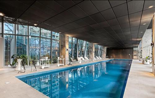 a swimming pool in a building with tables and chairs at Serenity Stayz - 3 Bedroom Apartment in Melbourne CBD in Melbourne