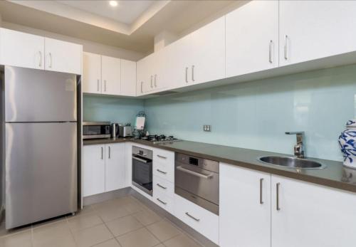 a kitchen with white cabinets and a stainless steel refrigerator at Domain 27 Apartment - Barton in Kingston 