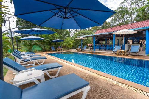 a swimming pool with lounge chairs and umbrellas next to a pool at Mook Lanta Eco Resort in Ko Lanta