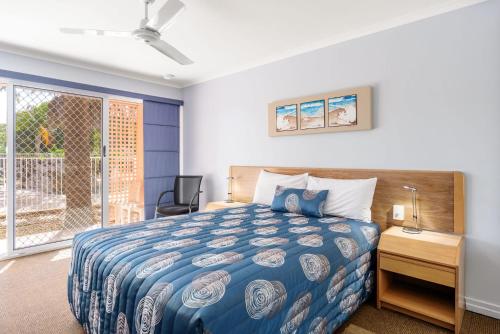 a bedroom with a bed and a desk and a window at Rainbow Sands Resort in Rainbow Beach