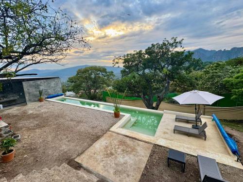 a swimming pool with an umbrella and a chair at Amara Tepoztlán in Tepoztlán