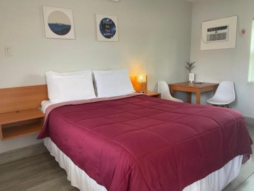 a bedroom with a large bed with a red blanket at Haven Hotel - Fort Lauderdale Airport & Cruise Port in Fort Lauderdale