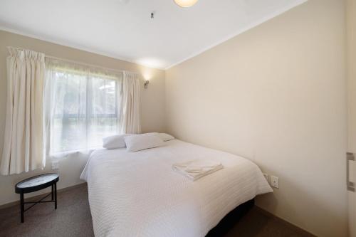 een slaapkamer met een wit bed en een raam bij Apartment 1 in Auckland