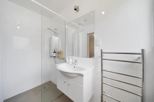 a white bathroom with a sink and a mirror at Apartment 1 in Auckland