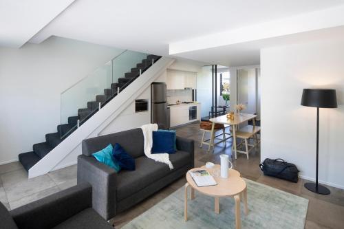 a living room with a couch and a staircase at Veriu Camperdown in Sydney