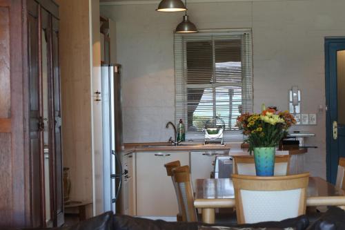 a kitchen with a refrigerator and a table with a vase of flowers at On the Beach in Hout Bay