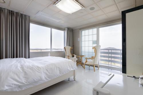 SongjuにあるHotel Gayaの白いベッドルーム(ベッド1台、テーブル、椅子付)