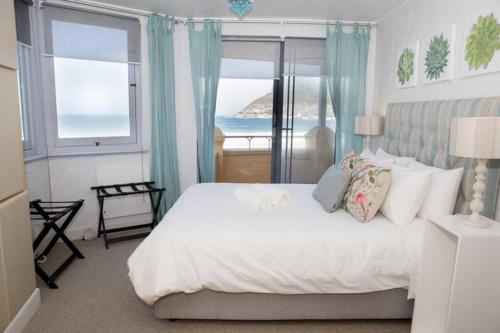 a bedroom with a bed with a view of the ocean at On the Beach in Hout Bay
