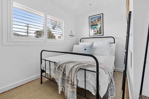 a bedroom with a bed with white sheets and a window at Shoal Heaven in Shoalhaven Heads
