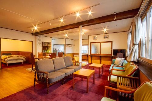 a living room with a couch and chairs and a bed at kODATEL コダテル函館大門 in Hakodate