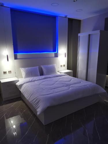 a bedroom with a large white bed with blue lights at Marina Town in Sohar