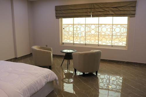 a bedroom with a bed and two chairs and a window at Marina Town in Sohar
