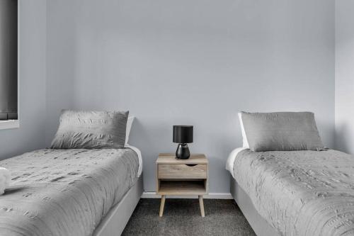a bedroom with two beds and a nightstand with a lamp at Heather Merimbula in Merimbula