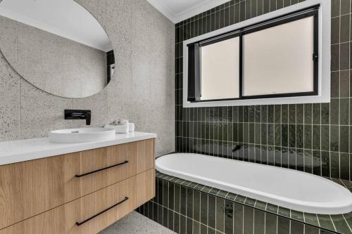 a bathroom with a tub and a sink and a mirror at Heather Merimbula in Merimbula