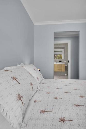 a white bed with two pillows on top of it at Heather Merimbula in Merimbula