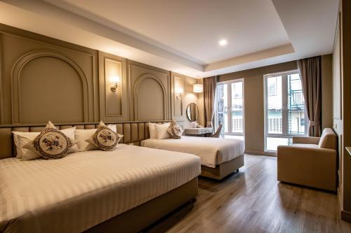 una habitación de hotel con 2 camas y una silla en Eurana Boutique Hotel en Chiang Mai