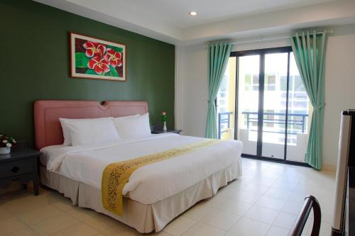 a bedroom with a large bed with green walls at The Corner in Patong Beach