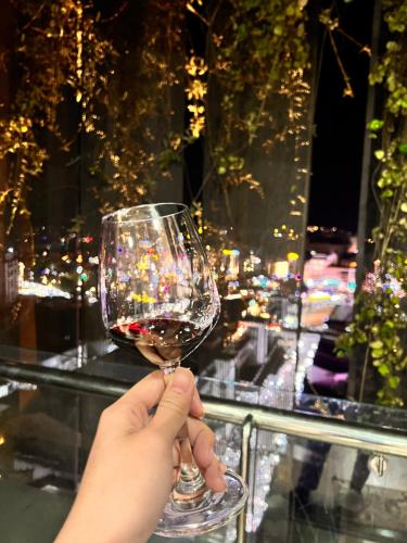 a person holding a glass of wine with a view at Đà Lạt center Ho Cozy in Da Lat