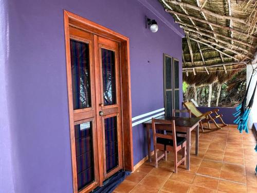 um quarto roxo com uma porta de madeira e uma mesa em Hotel Maya Luna Adults Only em Mahahual