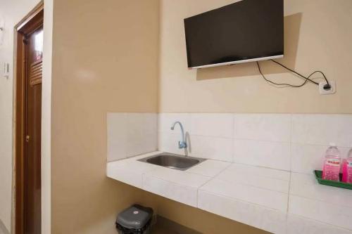 a bathroom with a sink and a tv on the wall at RedDoorz near UBL Lampung 2 in Kedaton