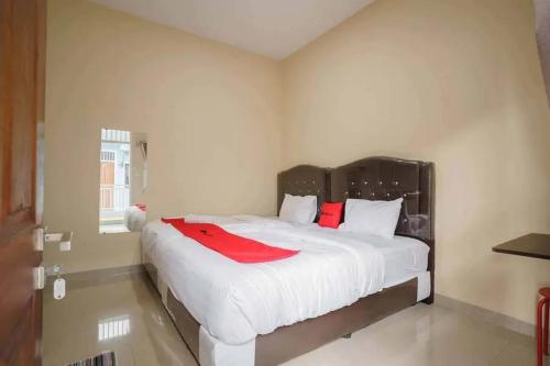 a bedroom with a large white bed with red pillows at RedDoorz near UBL Lampung 2 in Kedaton