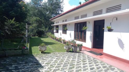 a white house with a courtyard with potted plants at Mahaweli Shades in Kandy