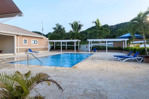 a swimming pool in a house with two blue chairs at Welcome to our Ocean View Villa! in Lucea