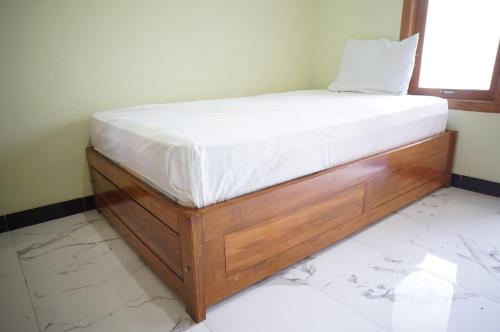 a bed with a wooden frame in a room at Spot On 93382 Gajayana Kost Female Only Syariah in Jenggrik